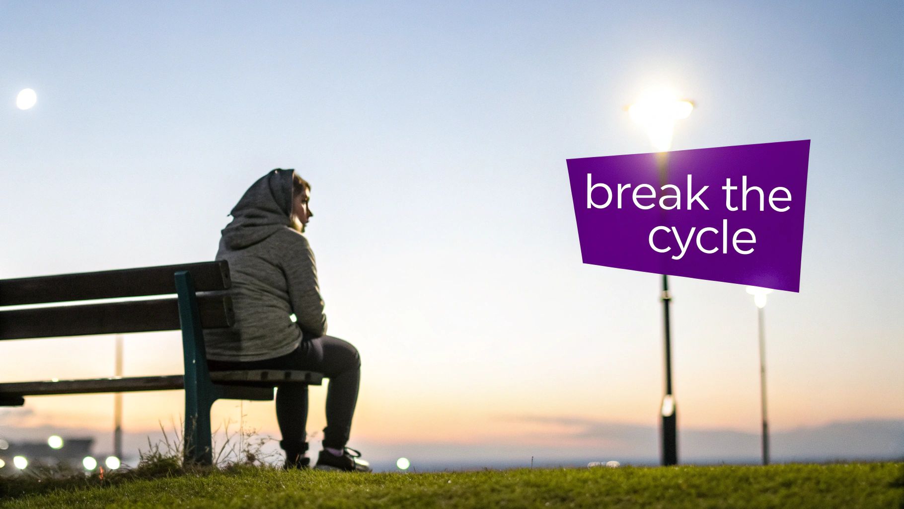 A person sits alone on a park bench at dusk, looking at the horizon, with a "break the cycle" sign.
