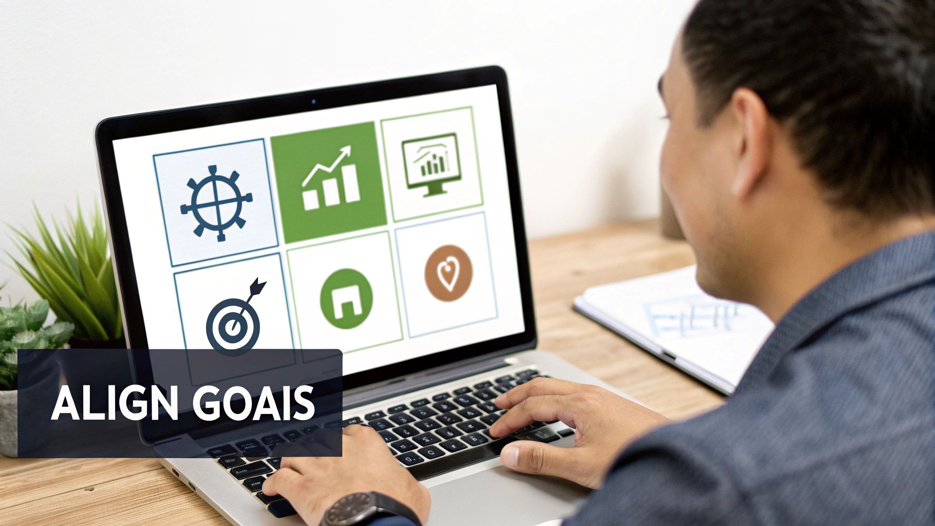 A person types on a laptop displaying icons representing business strategy, goals, and analytics.