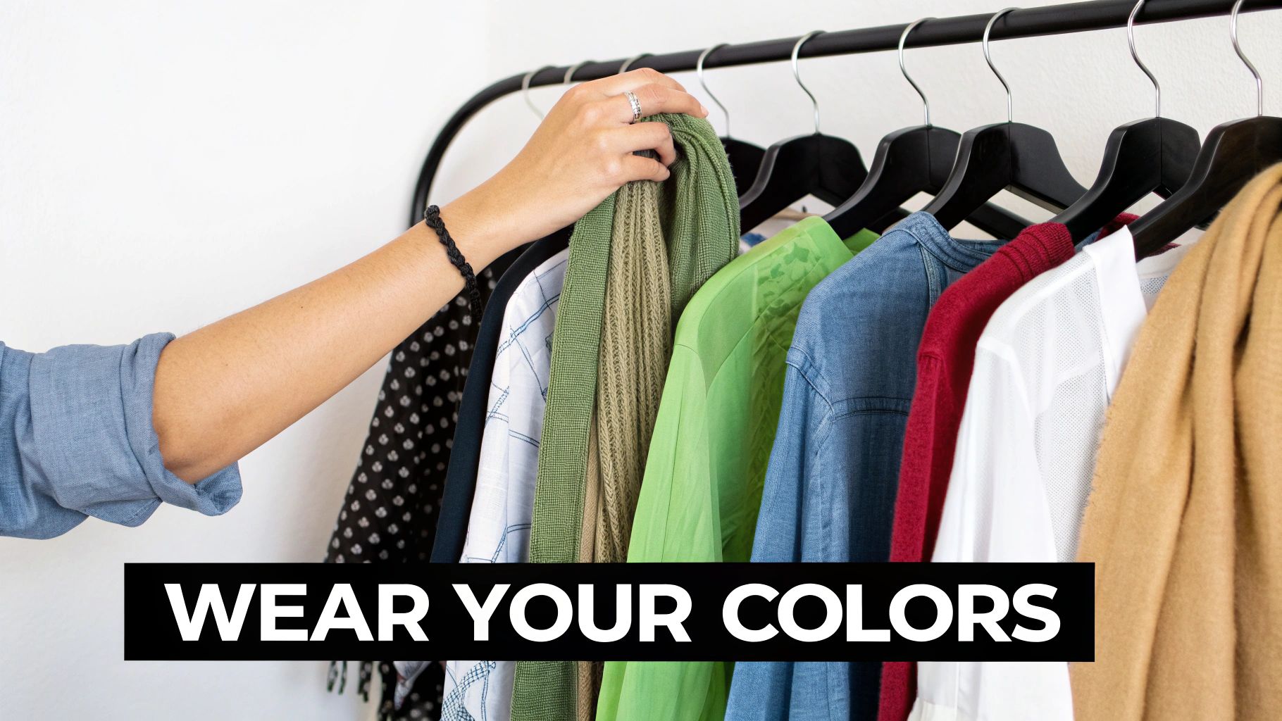 A hand selects a green garment from a rack of colorful clothes, with text 'WEAR YOUR COLORS'.