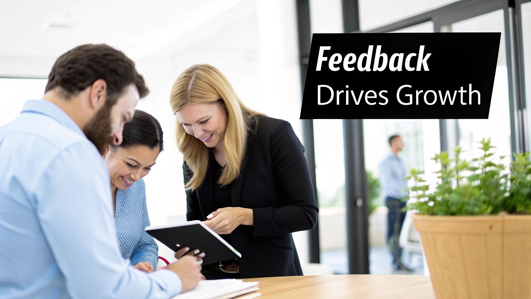 Smiling colleagues discuss and review information on a tablet, emphasizing feedback for growth.