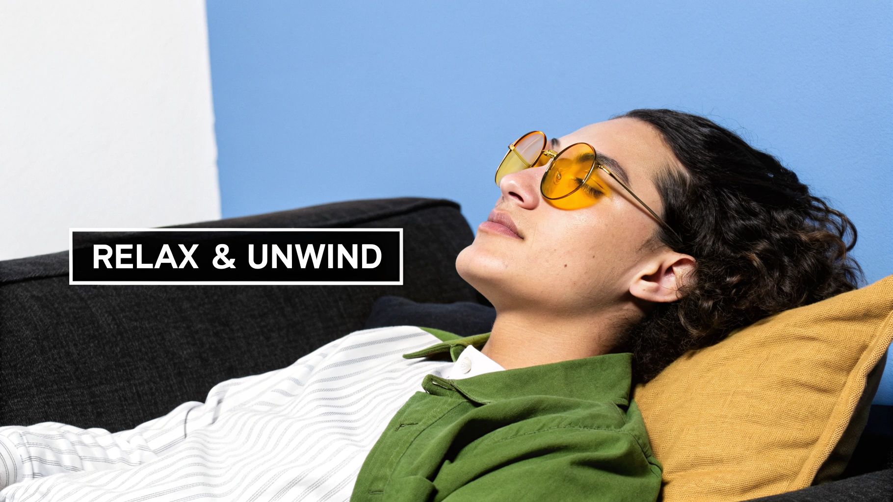 A woman wearing Element Lux amber blue light blocking glasses while relaxing on a couch