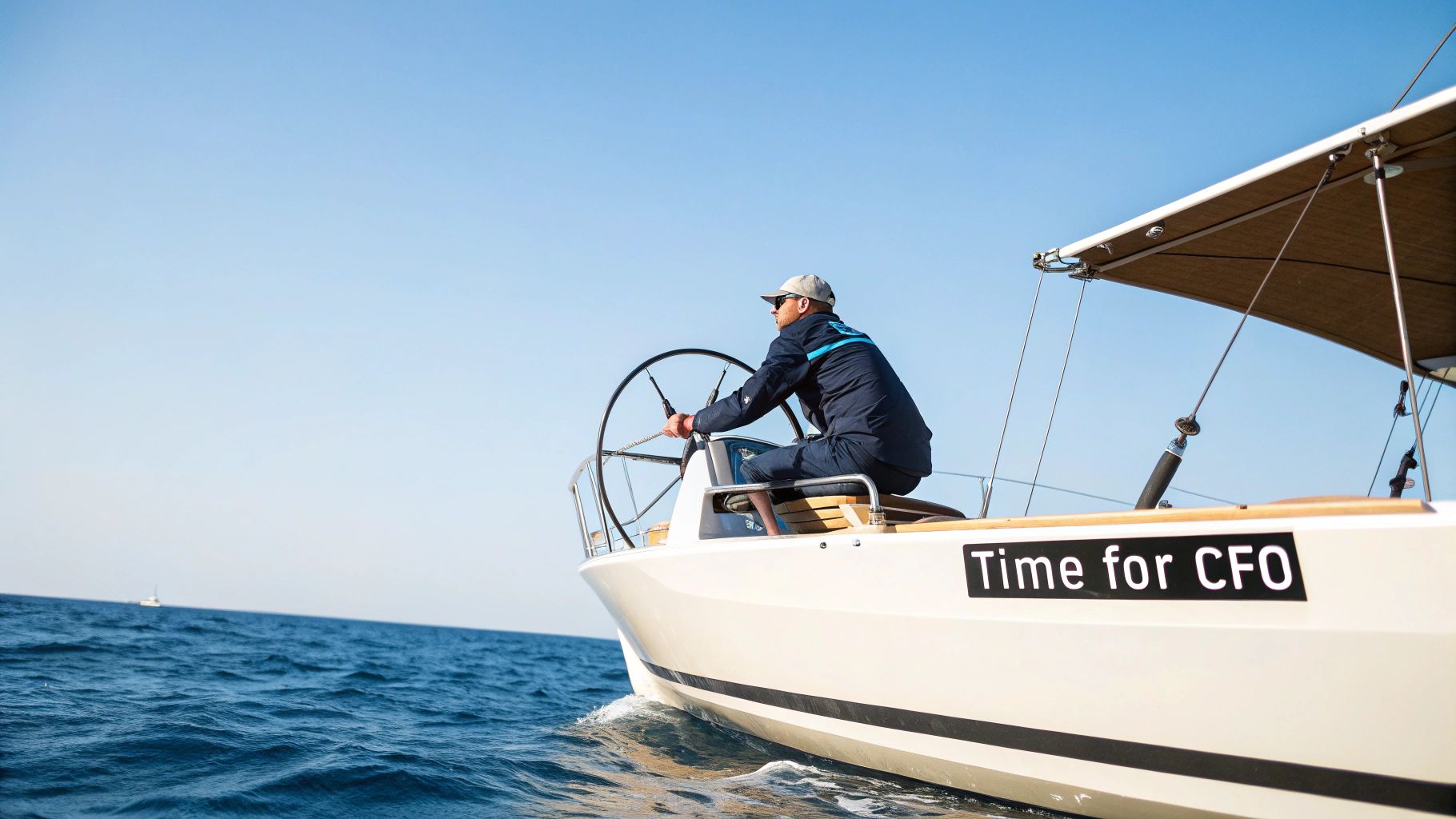 A man in a cap and jacket steers a white sailboat on the ocean under a clear blue sky.