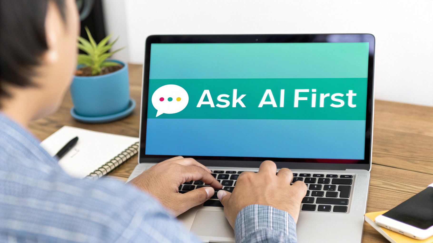 Over-the-shoulder view of a person typing on a laptop, screen shows 'Ask AI First'.