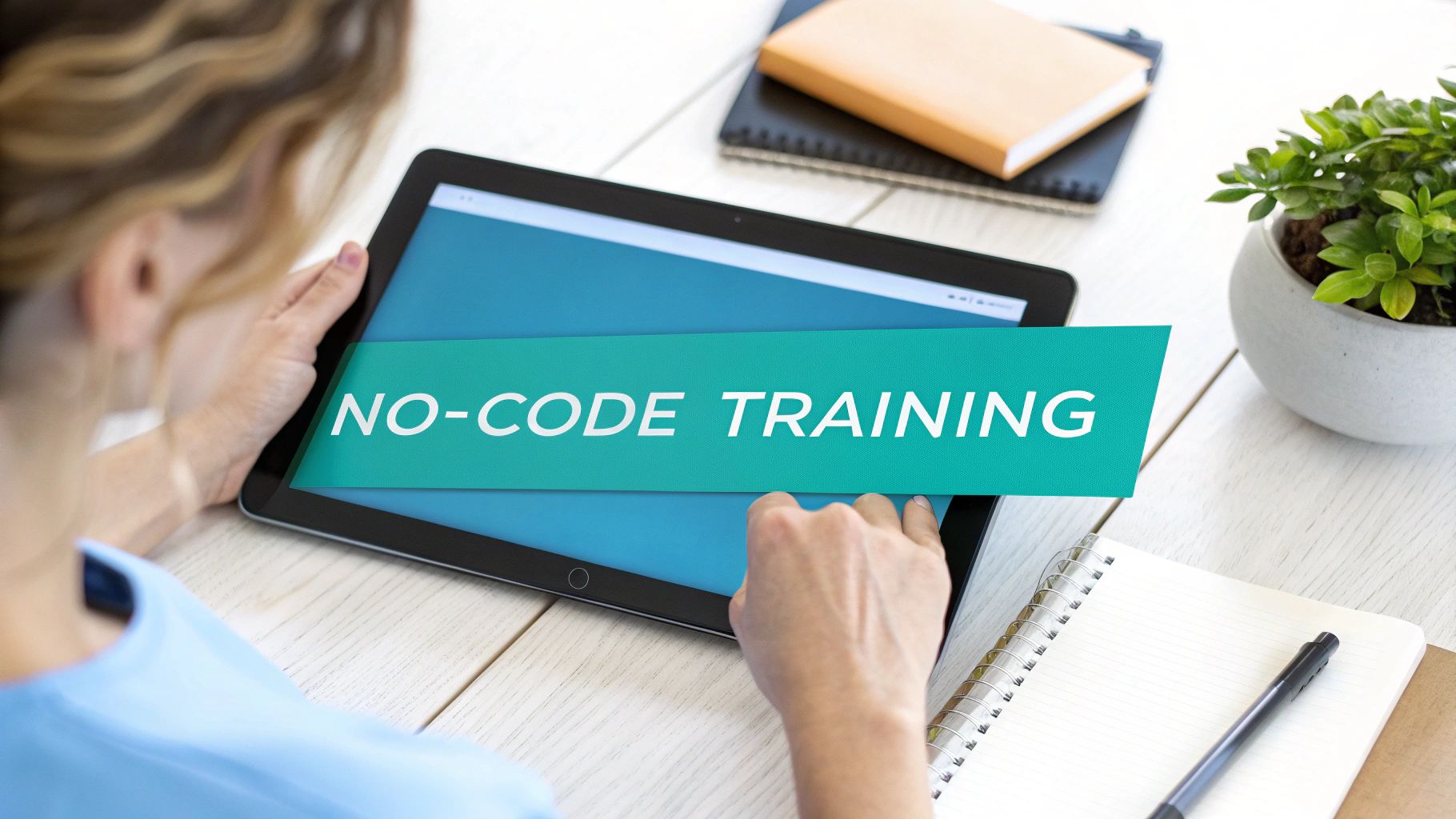 Overhead shot of a person using a tablet displaying 'NO-CODE TRAINING' on a desk.