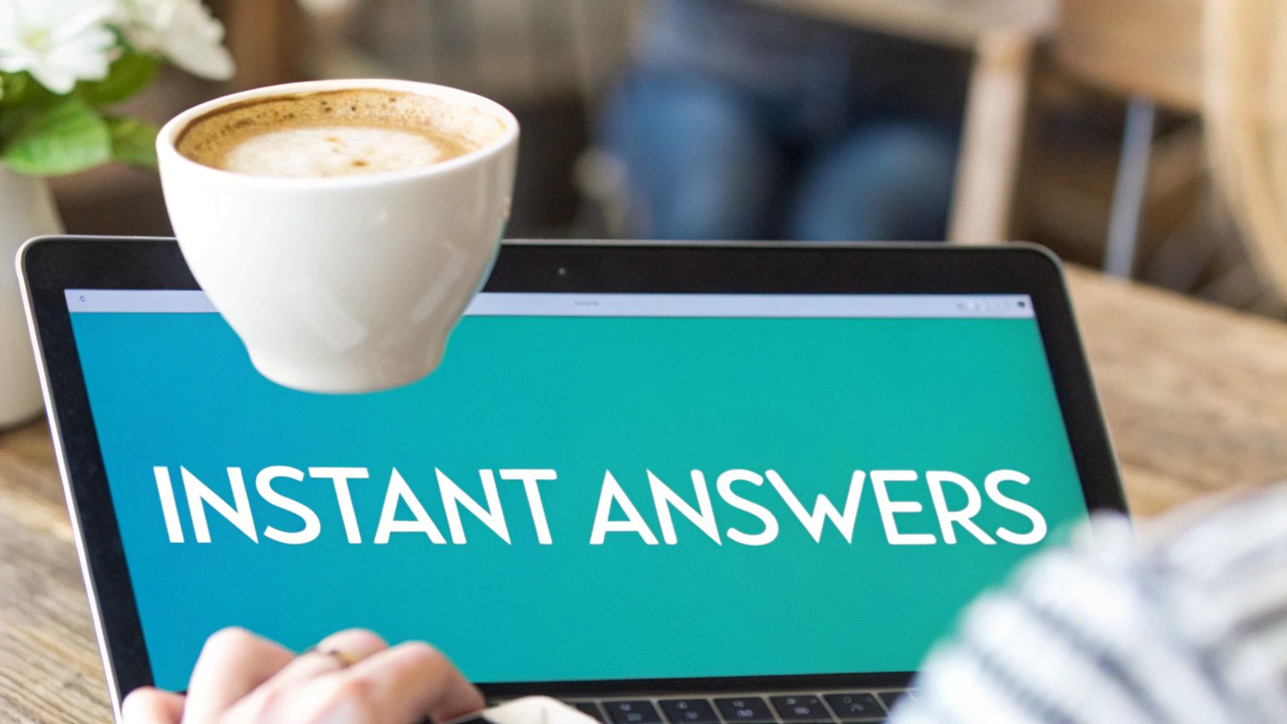 A person works on a laptop displaying 'INSTANT ANSWERS' with a coffee cup nearby.