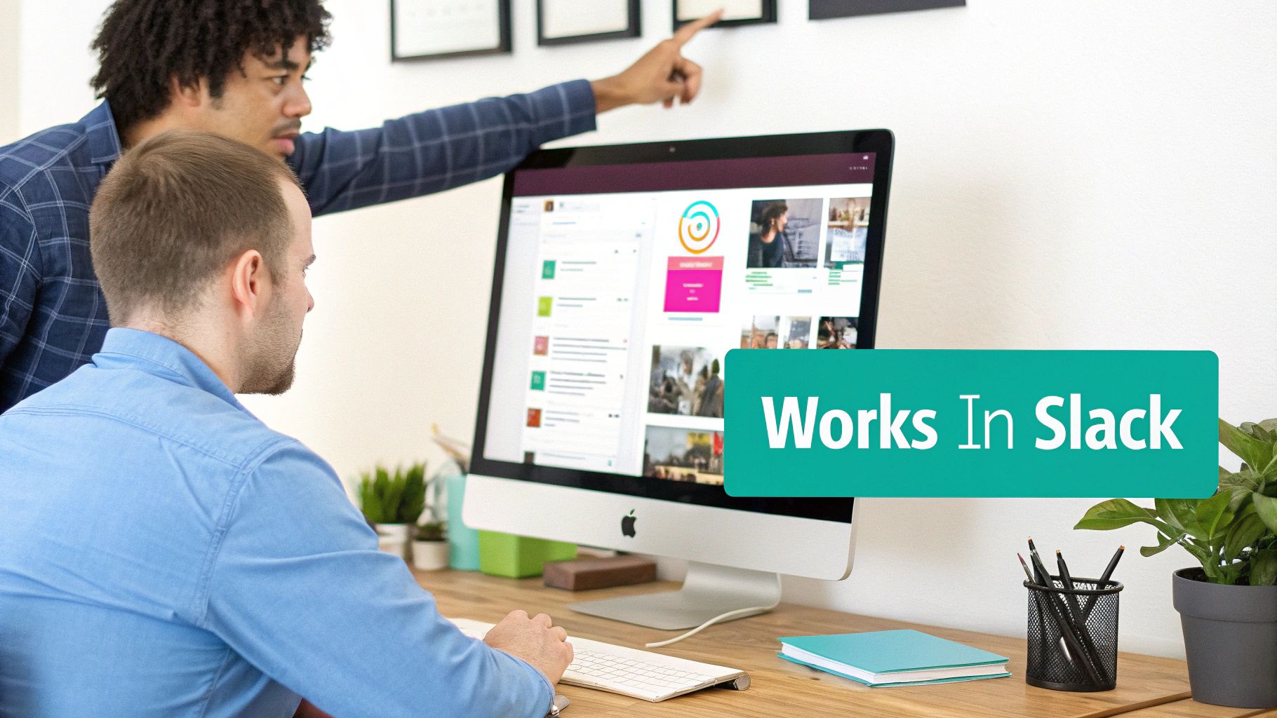 Two men collaborating at a desk, one pointing at the wall, the other typing on an iMac showing 'Works In Slack'.