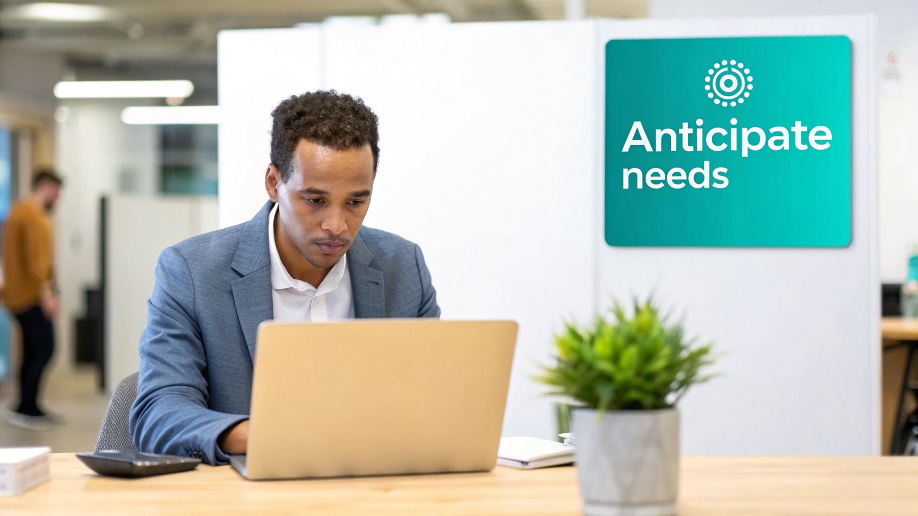 A focused man in a blazer works on a laptop at an office desk, promoting 'Anticipate needs'.