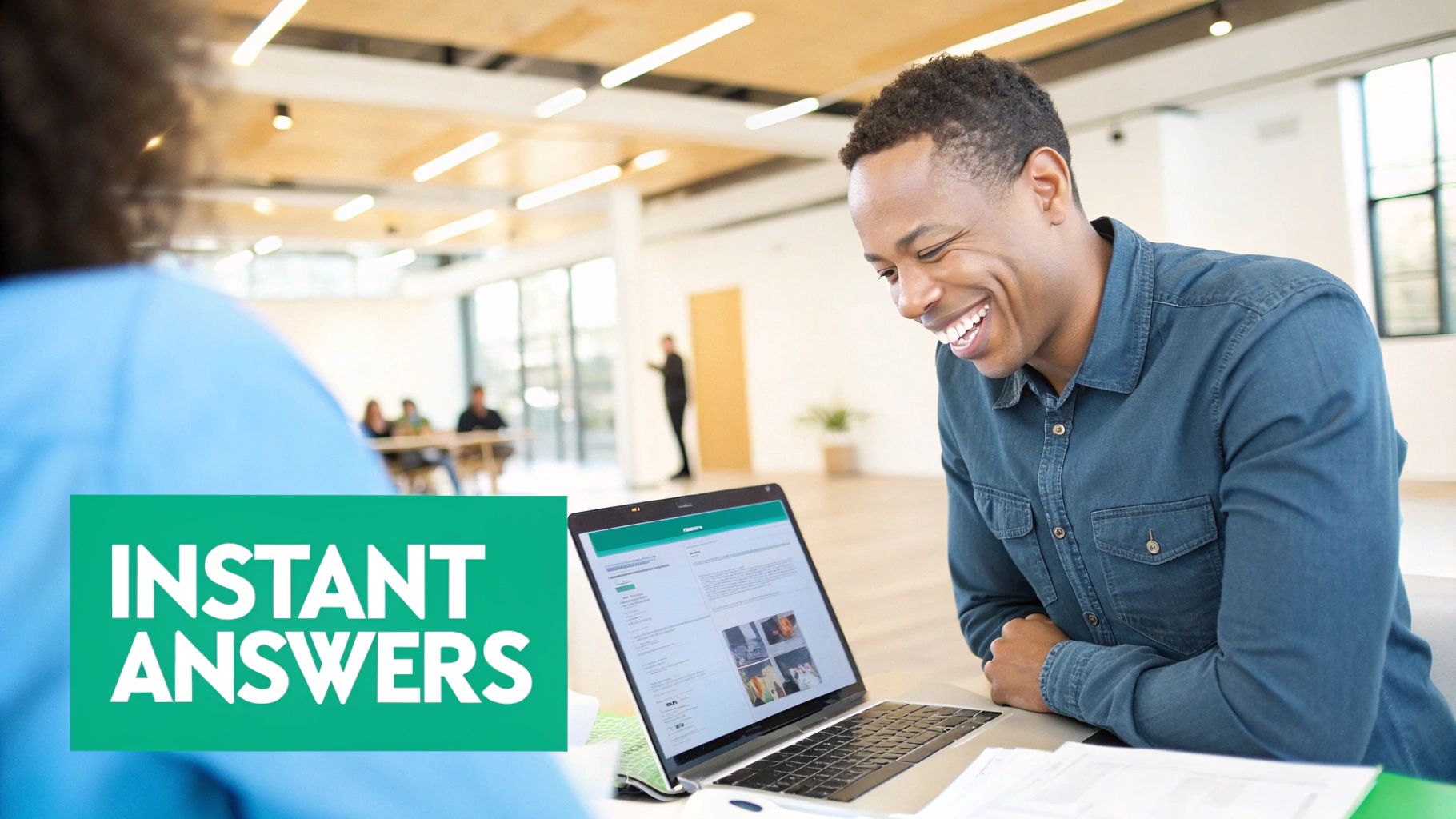 A smiling man looks at his laptop screen showing "Instant Answers" in a modern office setting.
