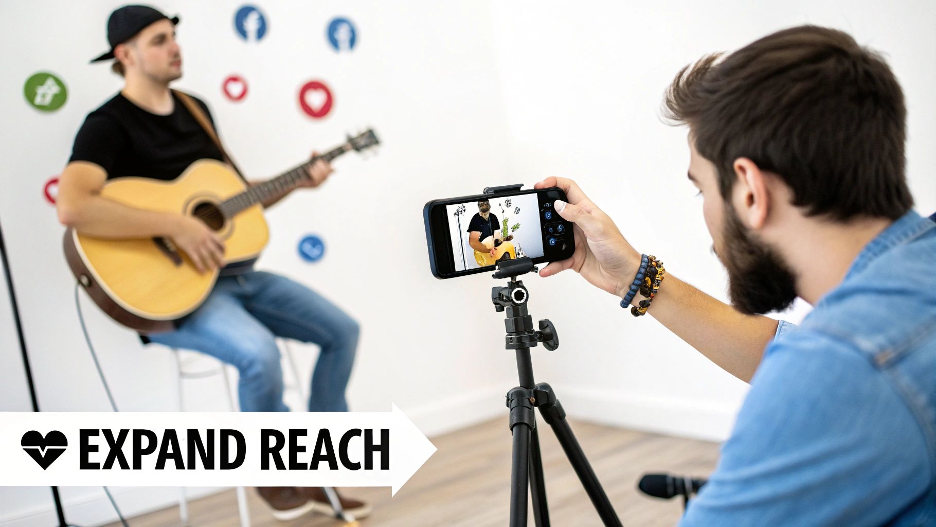 A musician plays an acoustic guitar while being filmed by a smartphone on a tripod for live streaming.