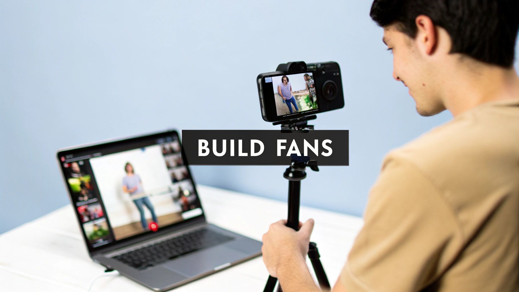 A person live-streaming with a smartphone on a tripod, with a laptop showing a video call.