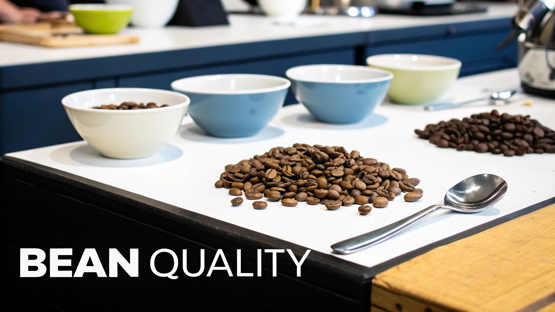Piles of roasted coffee beans and colorful bowls on a white counter for quality assessment