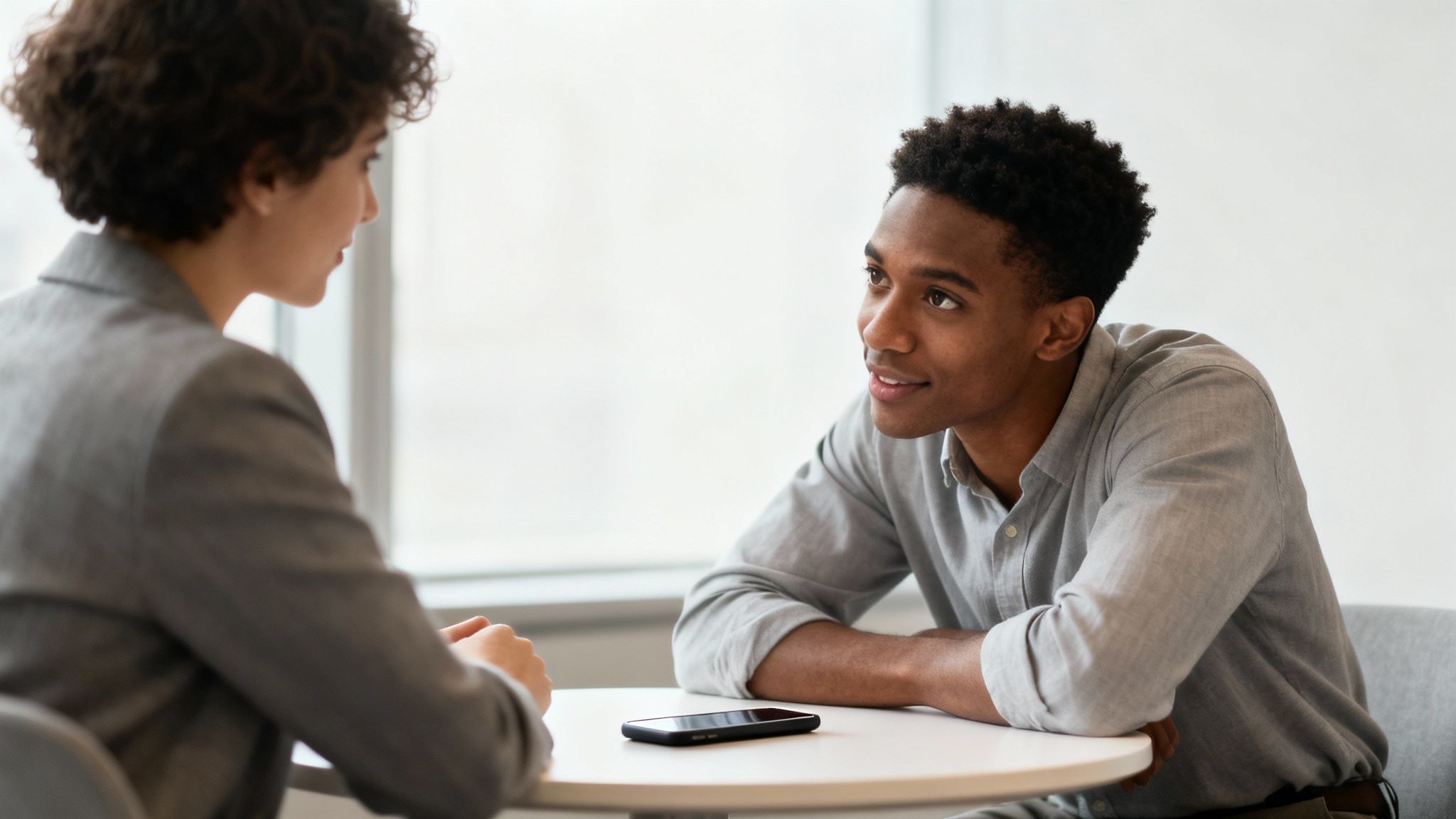 Two professionals having a focused business conversation at a table in modern office