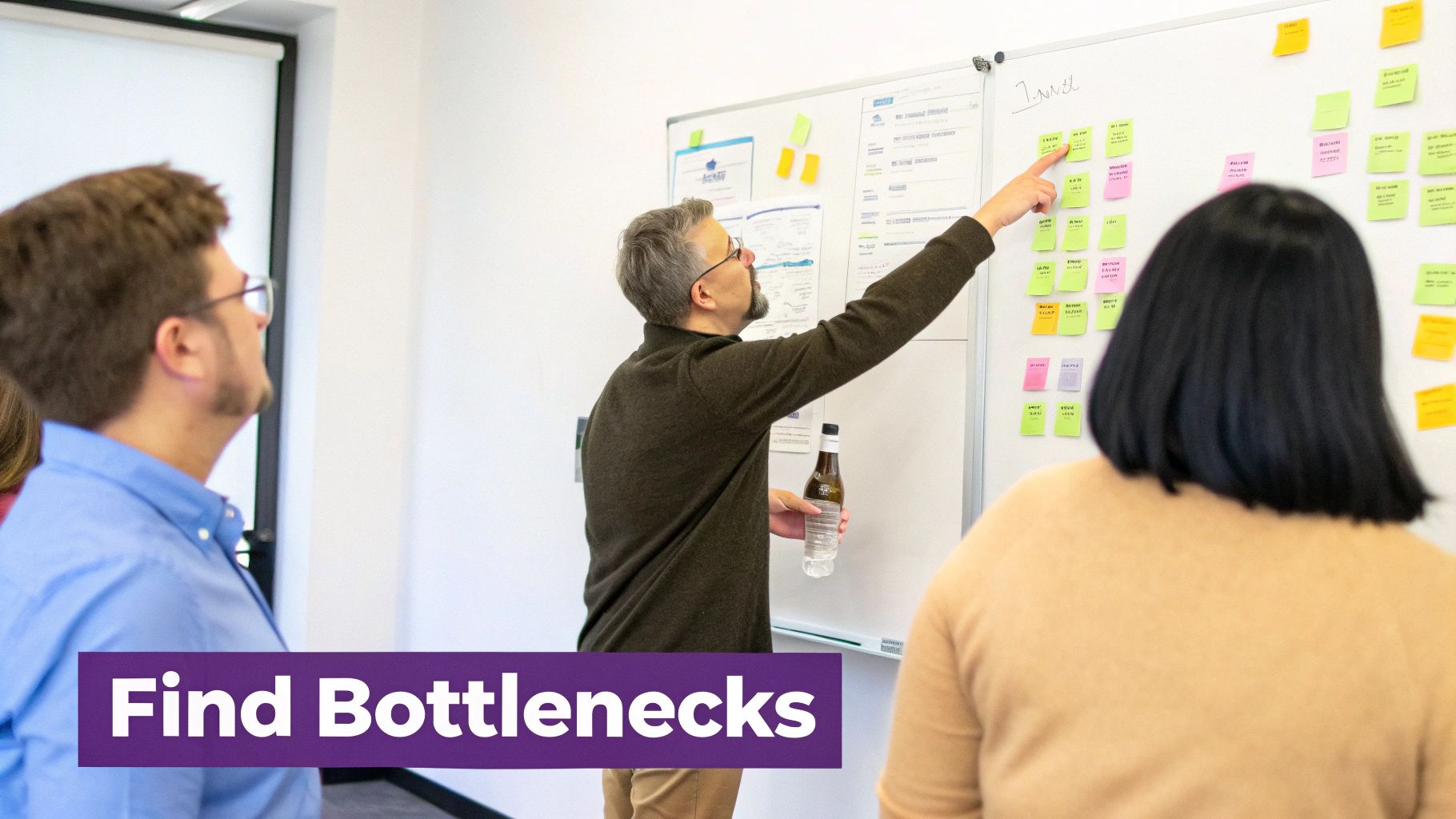 A team collaborating around a table with sticky notes, analyzing workflows.