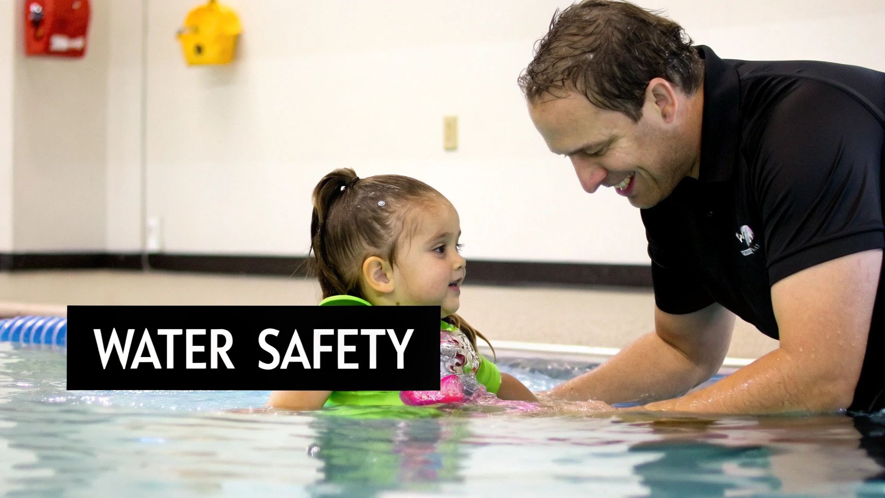 A smiling man and a young child in a swimming pool, engaged in a water safety lesson.
