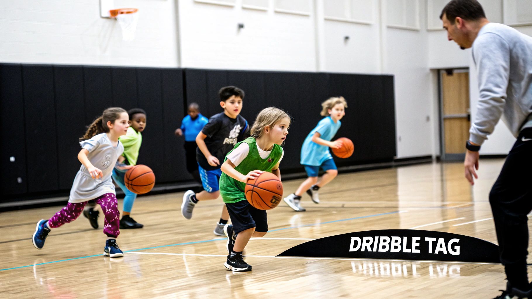 Young children dribbling basketballs during a Dribble Tag game with a coach in a gym.