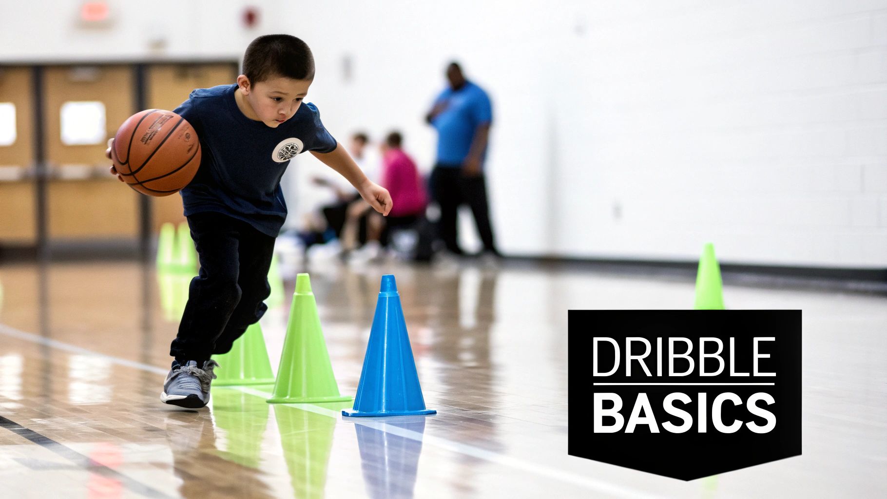 A young boy dribbles a basketball through cones on a gym floor during a "Dribble Basics" class.