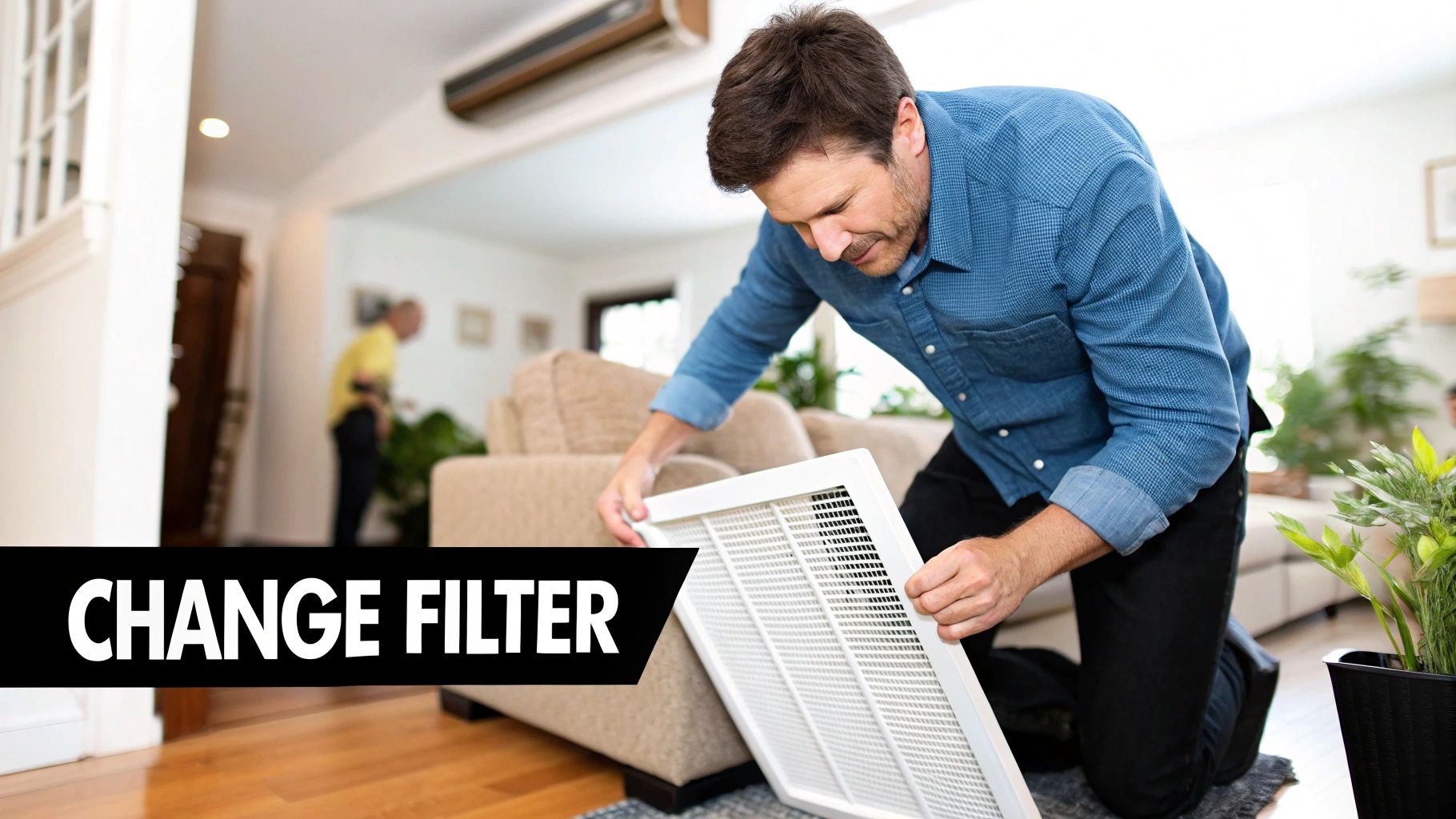 A man in a blue shirt kneels to remove a vent cover, likely to change an AC filter.