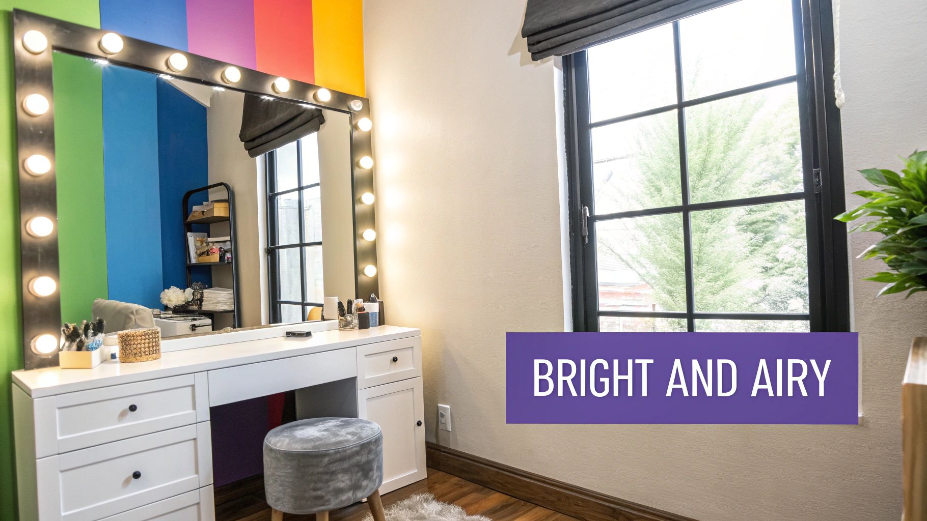 A bright vanity area with a lighted mirror, white desk, grey stool, and colorful striped wall.