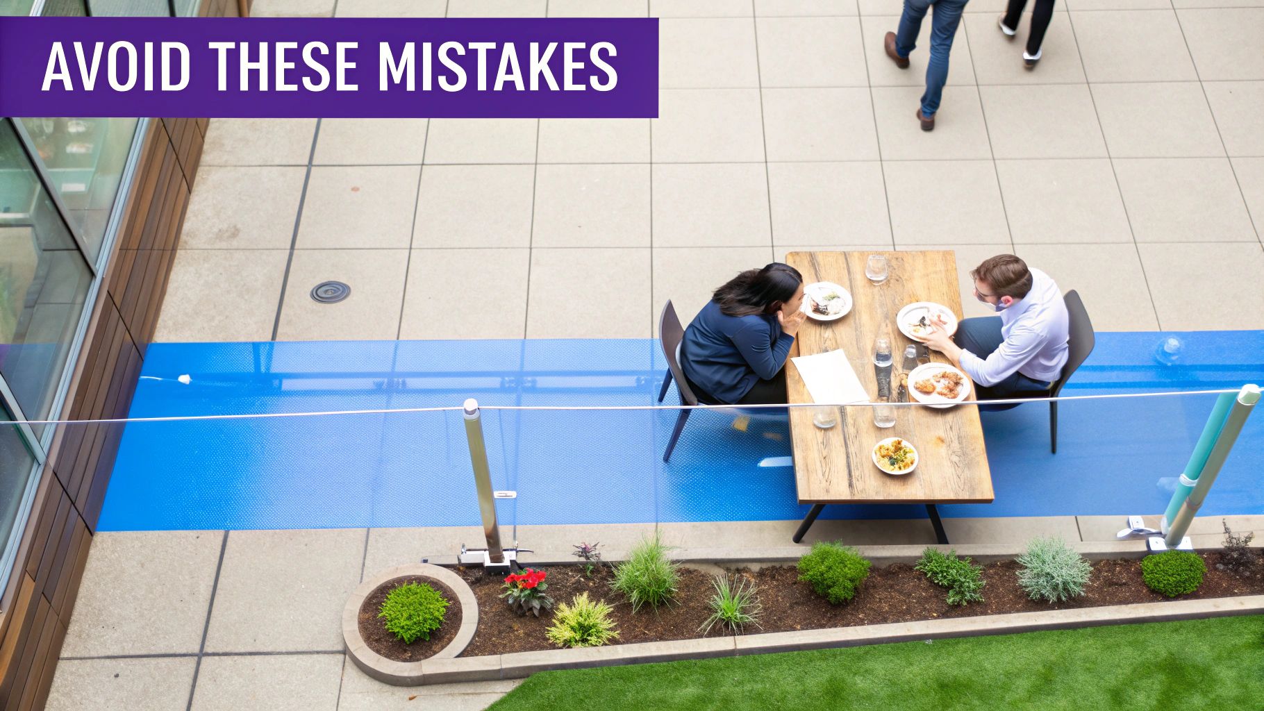 Two professionals eat lunch at an outdoor table in a well-designed urban patio area with blue pathways.
