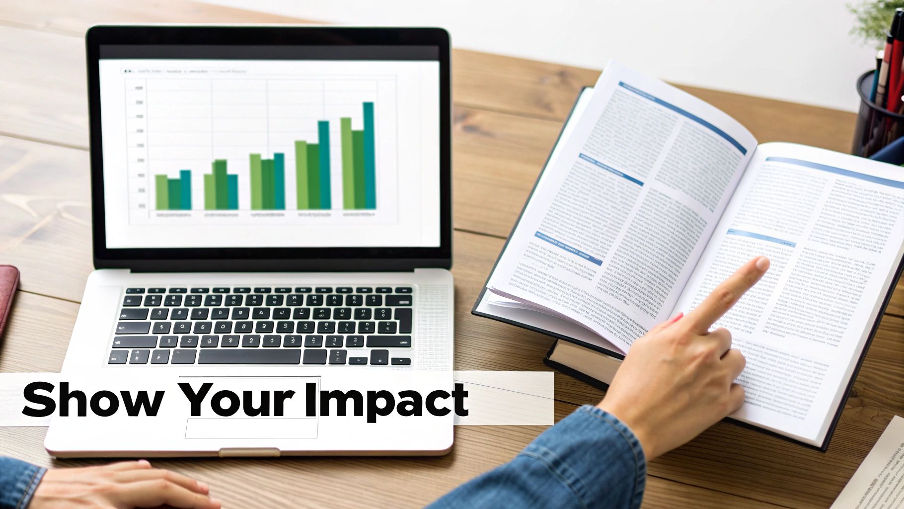 Person analyzing data on a laptop with a bar chart and reading an open book on a desk.