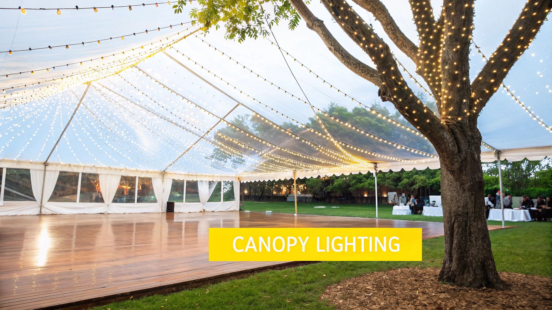 Your Guide to Magical Wedding String Lighting in Knoxville An outdoor wedding tent with a wooden dance floor, illuminated by string lights on the canopy and trees.