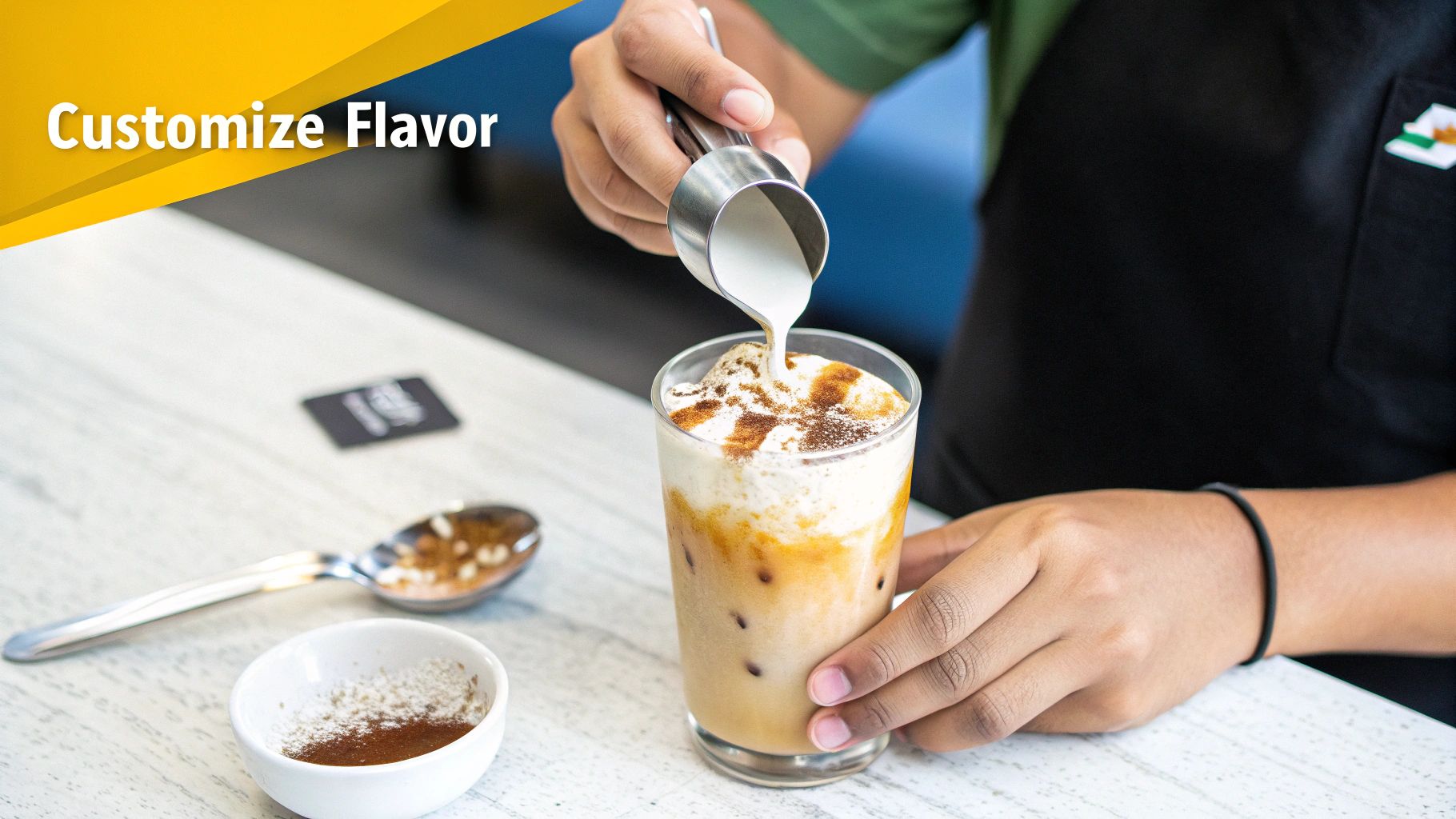 A barista customizes an iced coffee by pouring cream over whipped topping, enhancing its flavor.