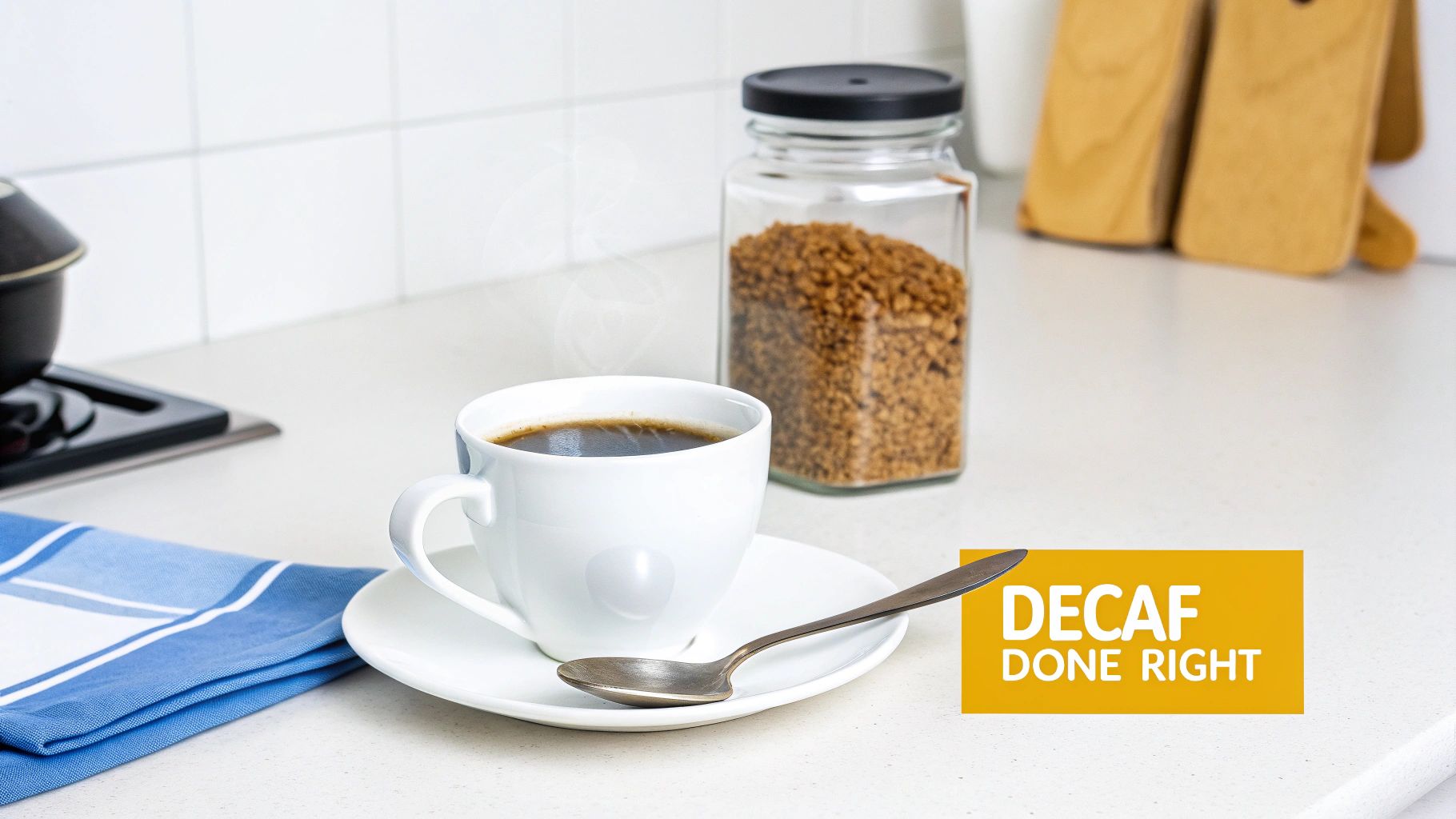 A white mug of steaming decaf coffee with a jar of instant coffee granules on a kitchen counter.