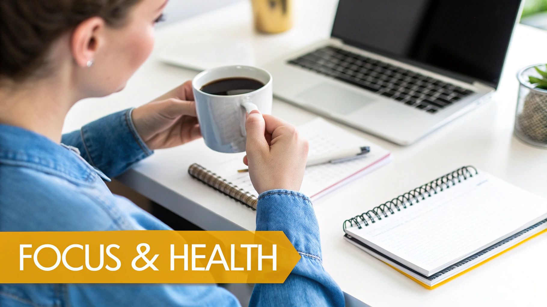 A person's hands holding a white mug of instant coffee, with a laptop open in the background.