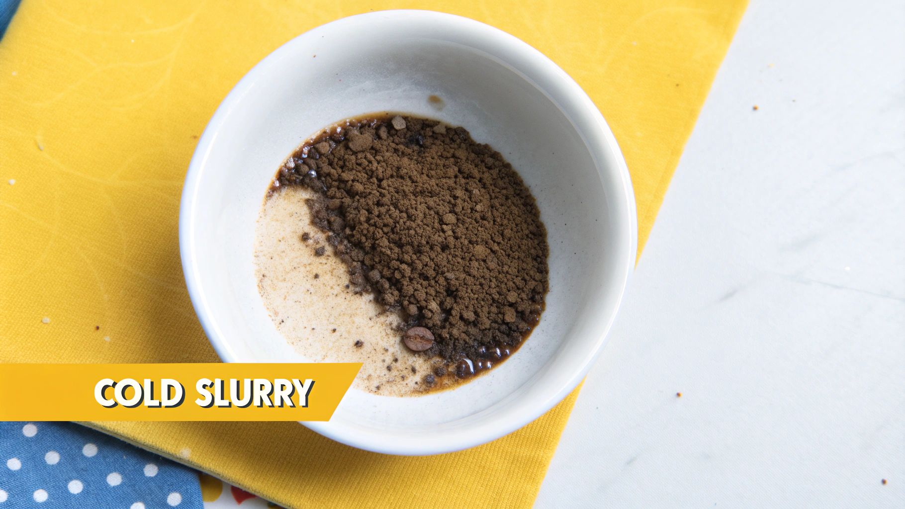 A hand stirring a dark coffee paste in the bottom of a clear mug.