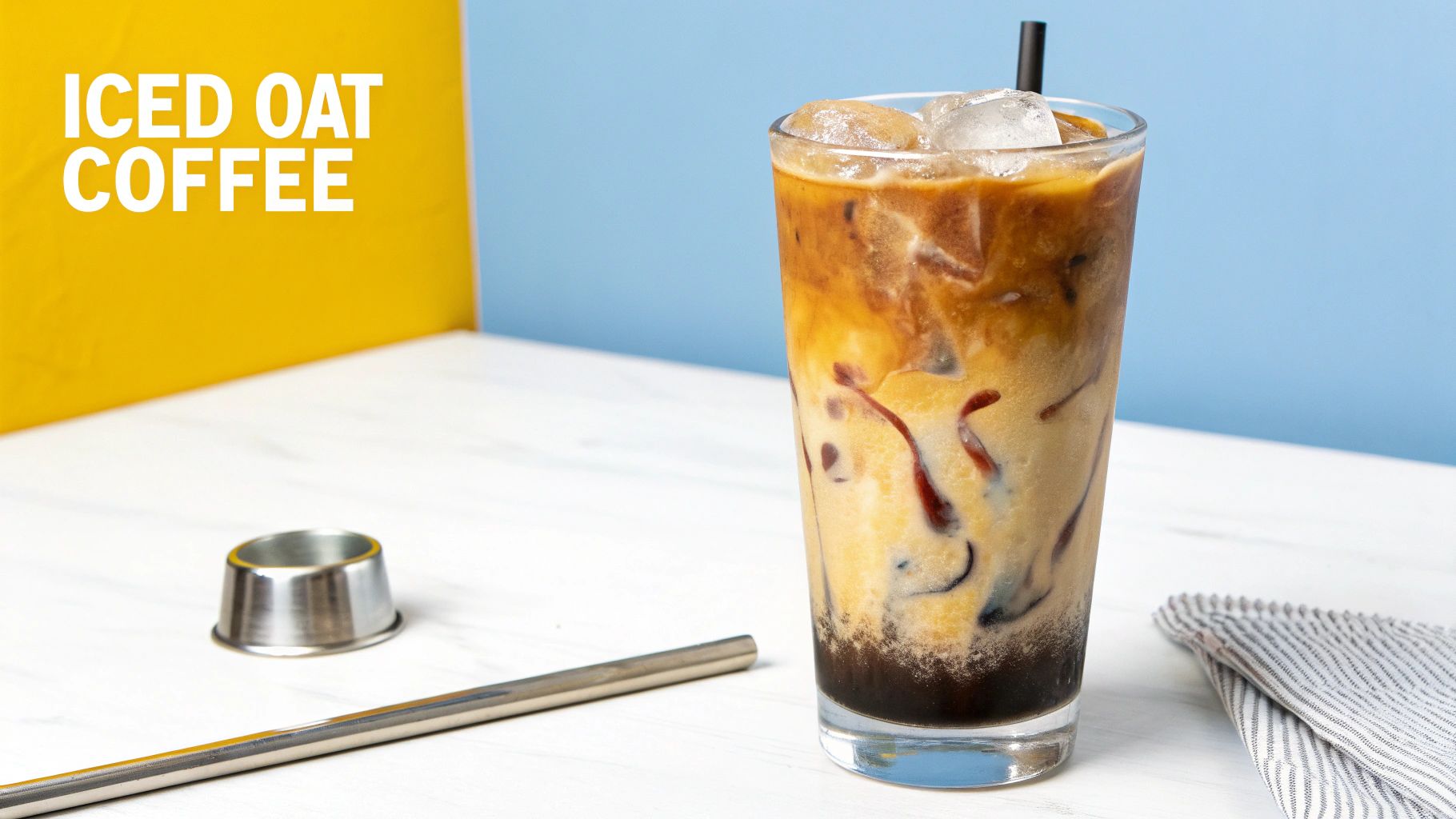 A vibrant iced oat coffee in a tall glass with layered coffee and milk, a straw, and ice.