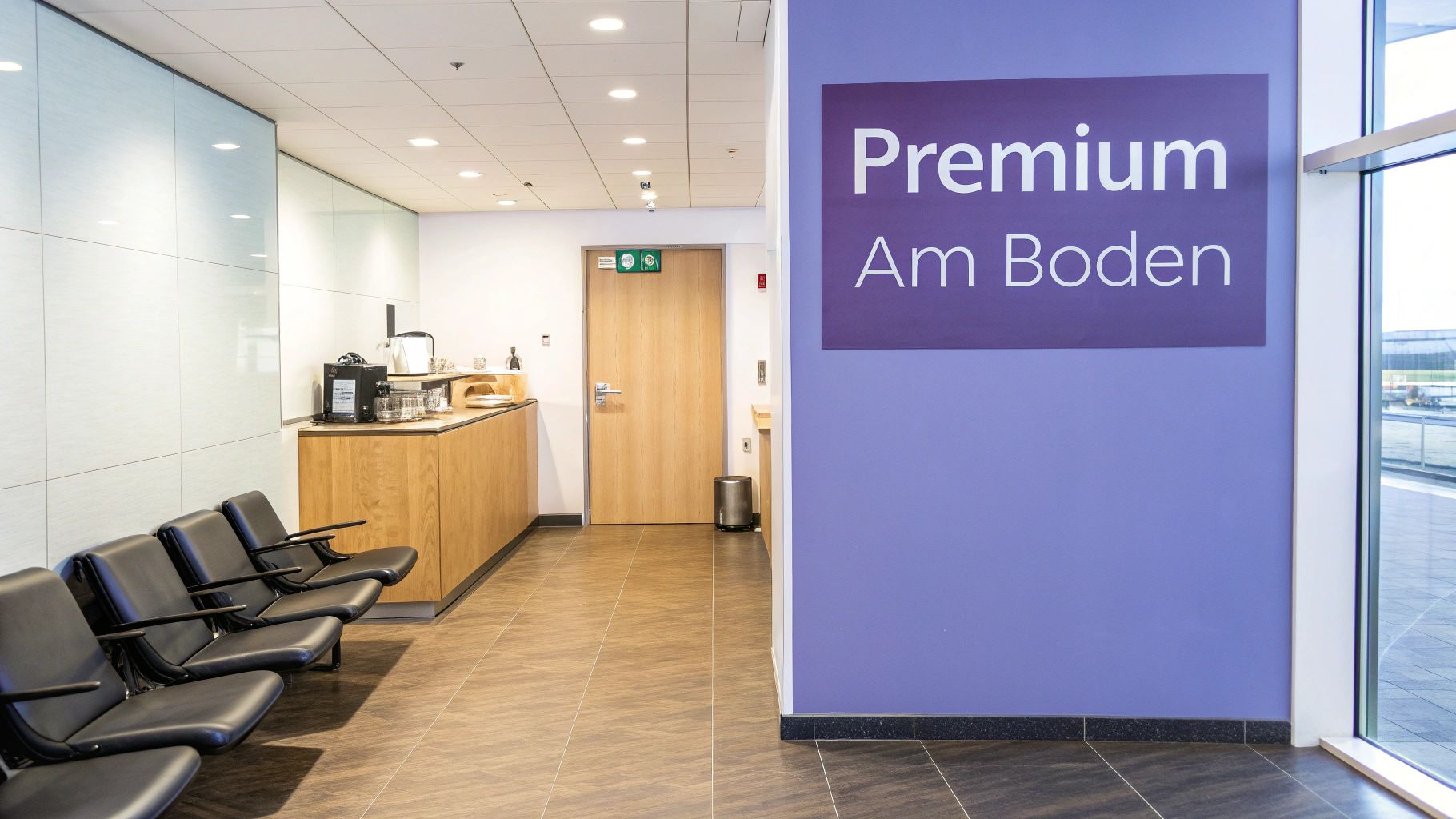 Sitzbereich in einer Premium-Lounge mit Theke, schwarzen Stühlen und einem lila Schild.
