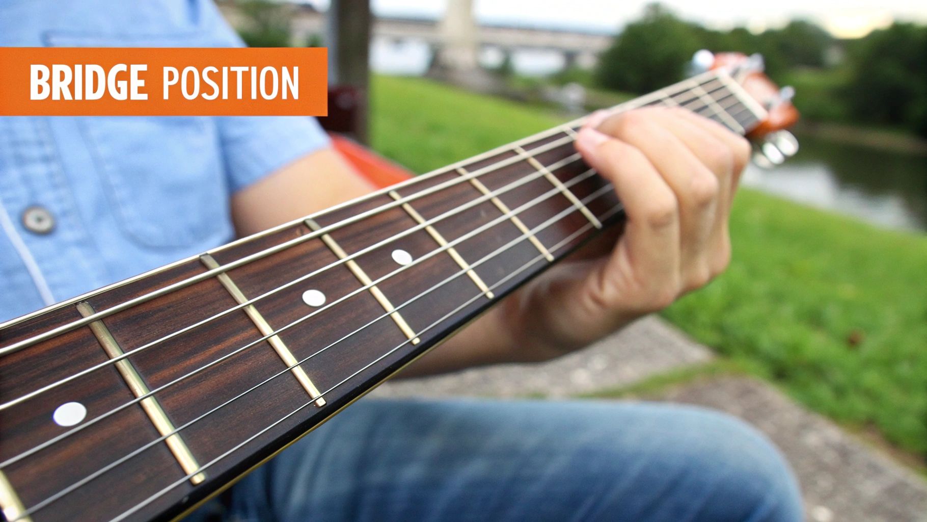 Close-up of a hand playing guitar on a fretboard with an orange 'BRIDGE POSITION' text banner.
