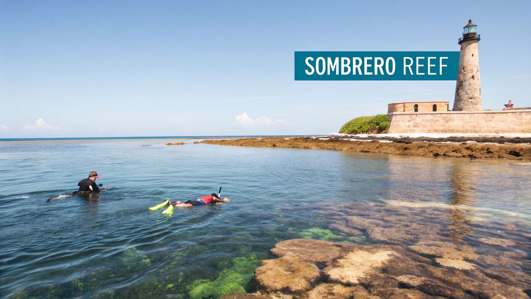 A historic lighthouse stands in the middle of a turquoise ocean with a coral reef visible below the surface.