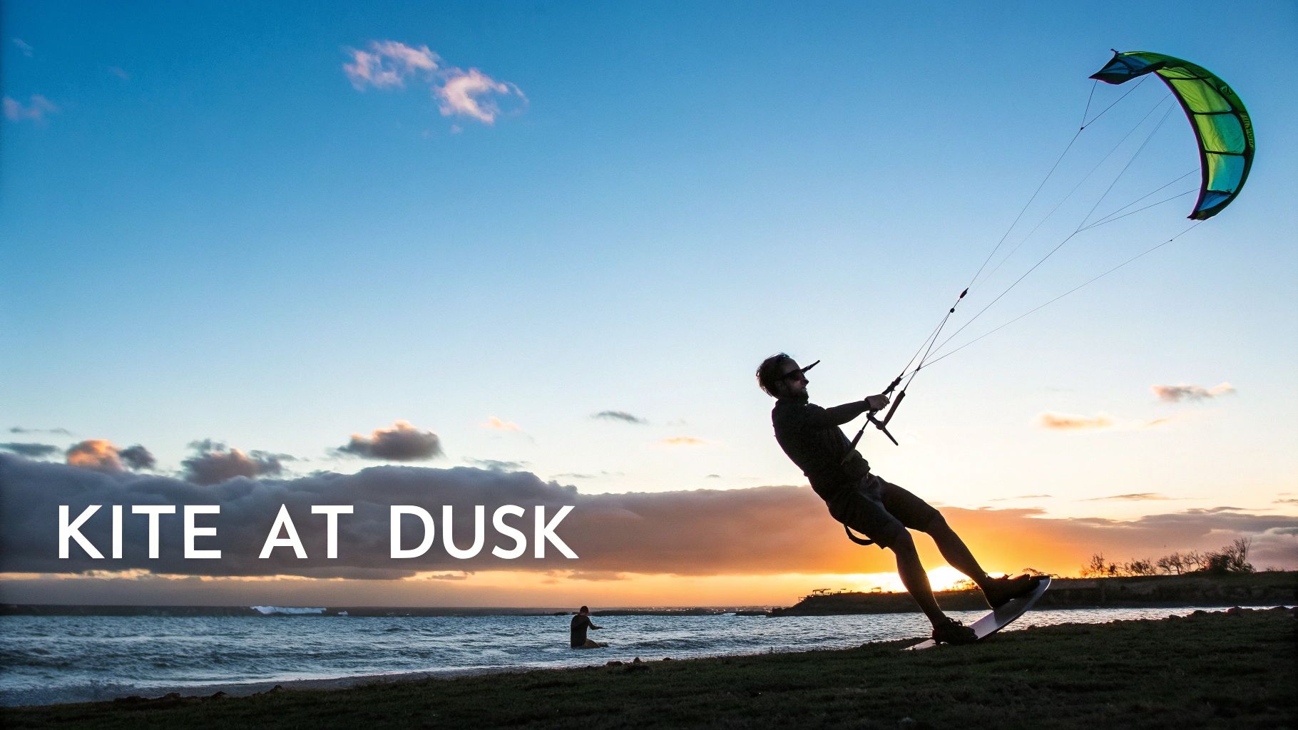 Kitesurfer silhouetted against colorful sunset sky while kiteboarding on ocean water at dusk