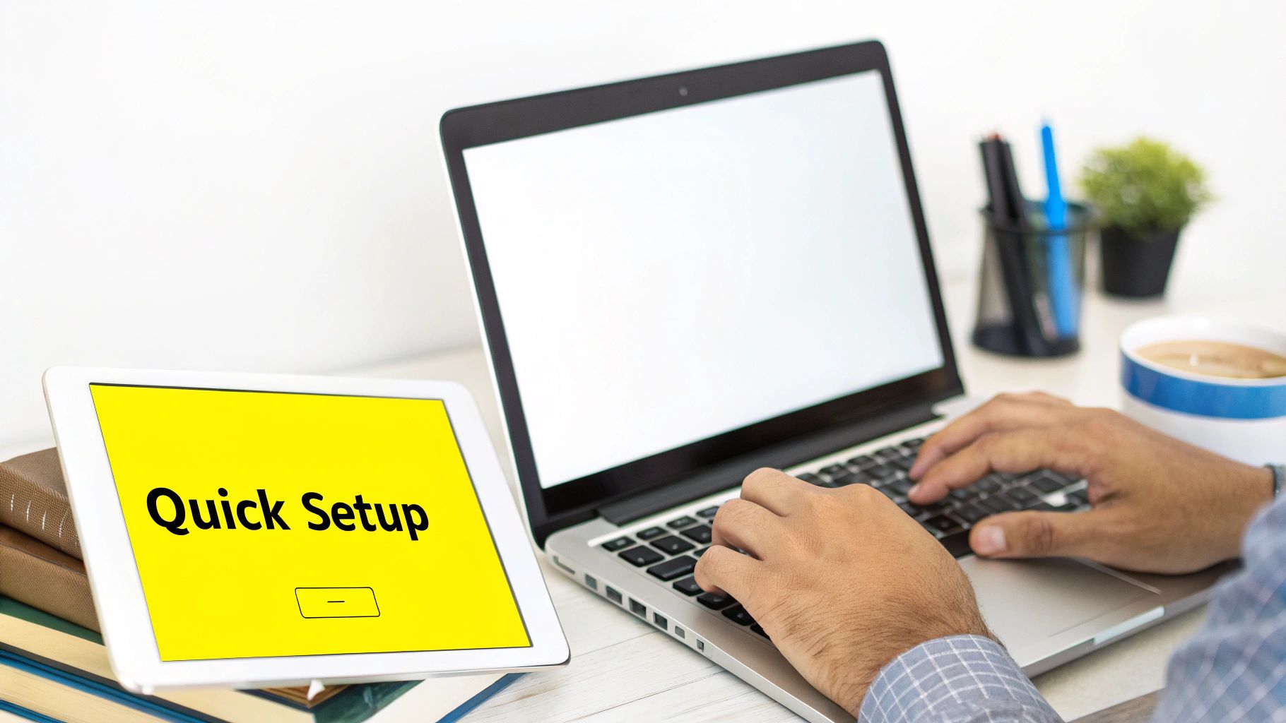 A person works on a laptop, a tablet displays 'Quick Setup', with office items and coffee.