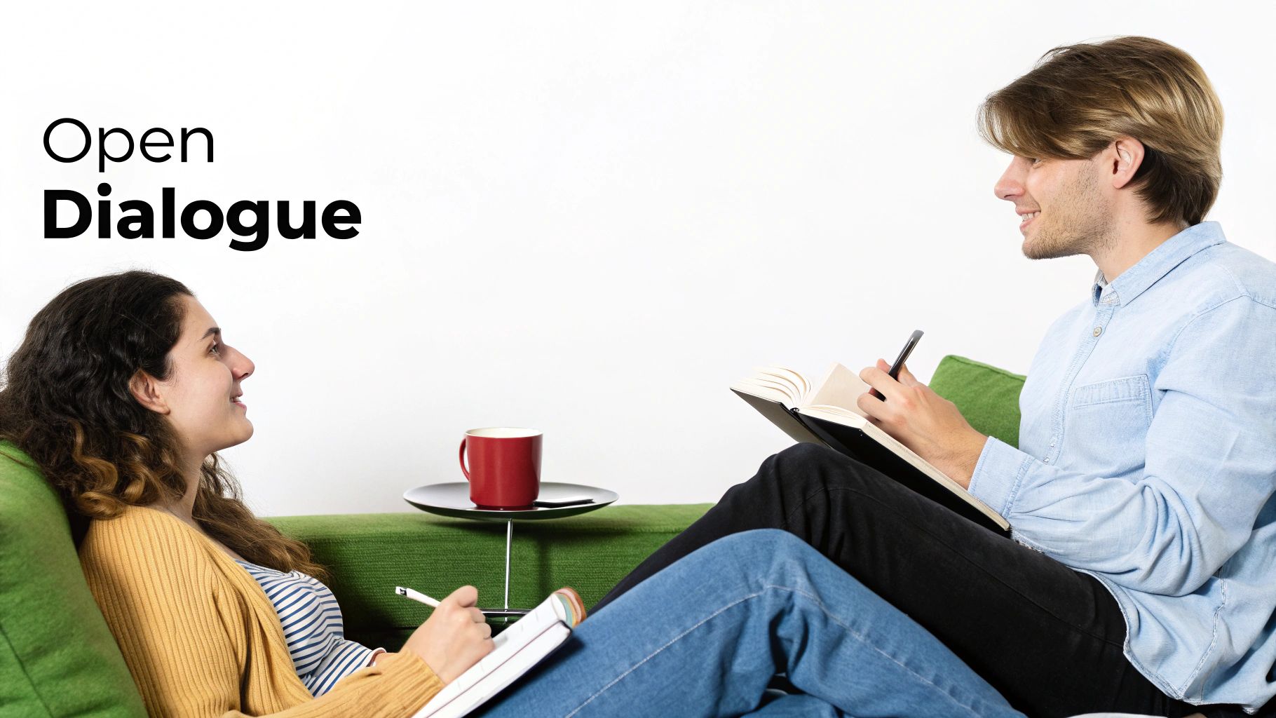 Two smiling people on a green couch engaging in an open dialogue, writing in notebooks.