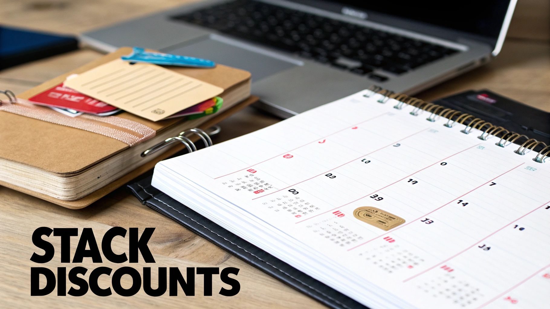 A close-up of a desk with a laptop, a notebook, and an open calendar, suggesting planning and finding discounts.