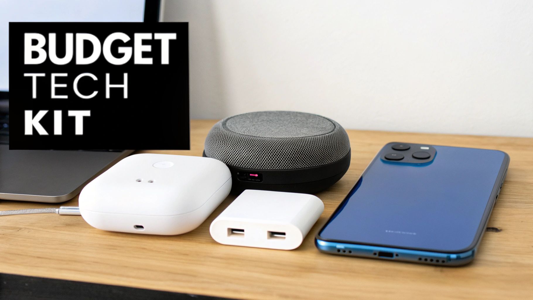 A budget tech kit with a blue smartphone, smart speaker, charger, and power bank on a wooden desk.