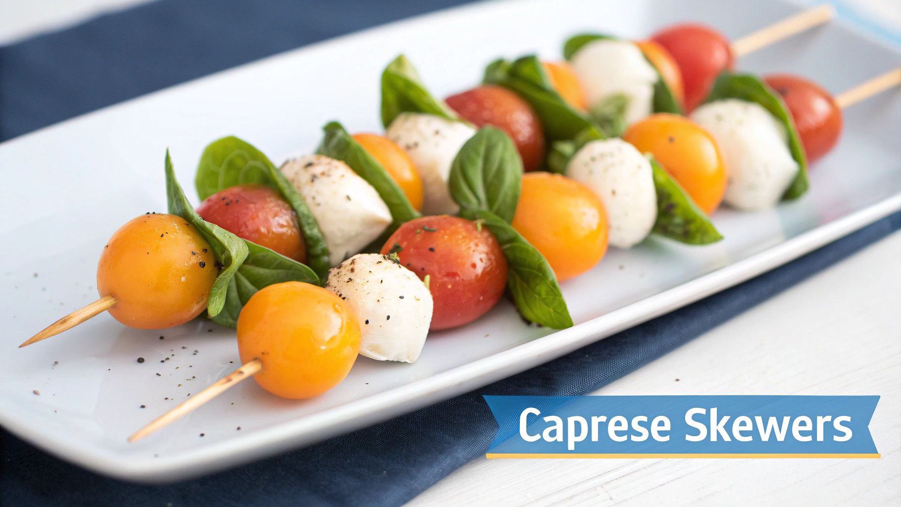 Close-up of colorful Caprese skewers with cherry tomatoes, mozzarella, and basil on a white platter.