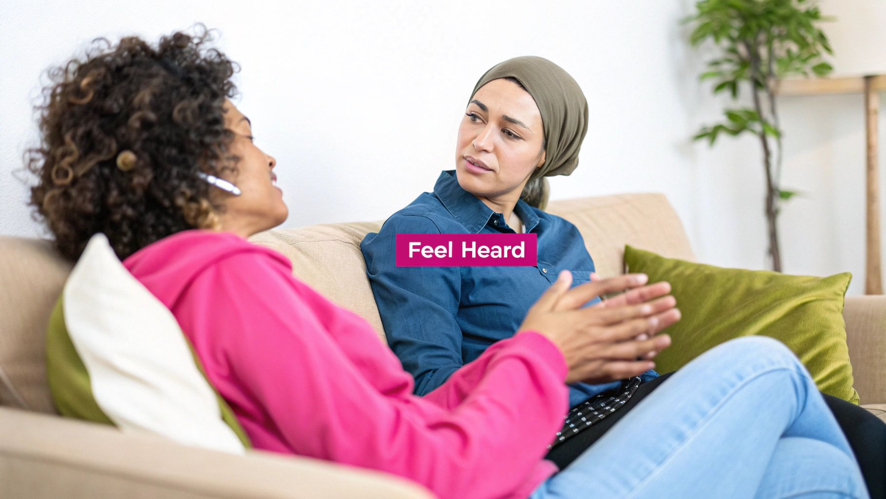 Two women on a couch having a deep conversation, one speaking, the other listening intently.