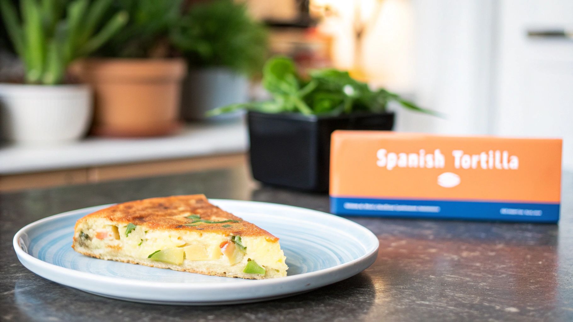 Slice of Spanish tortilla on a blue plate, with an orange Spanish Tortilla box and plants.