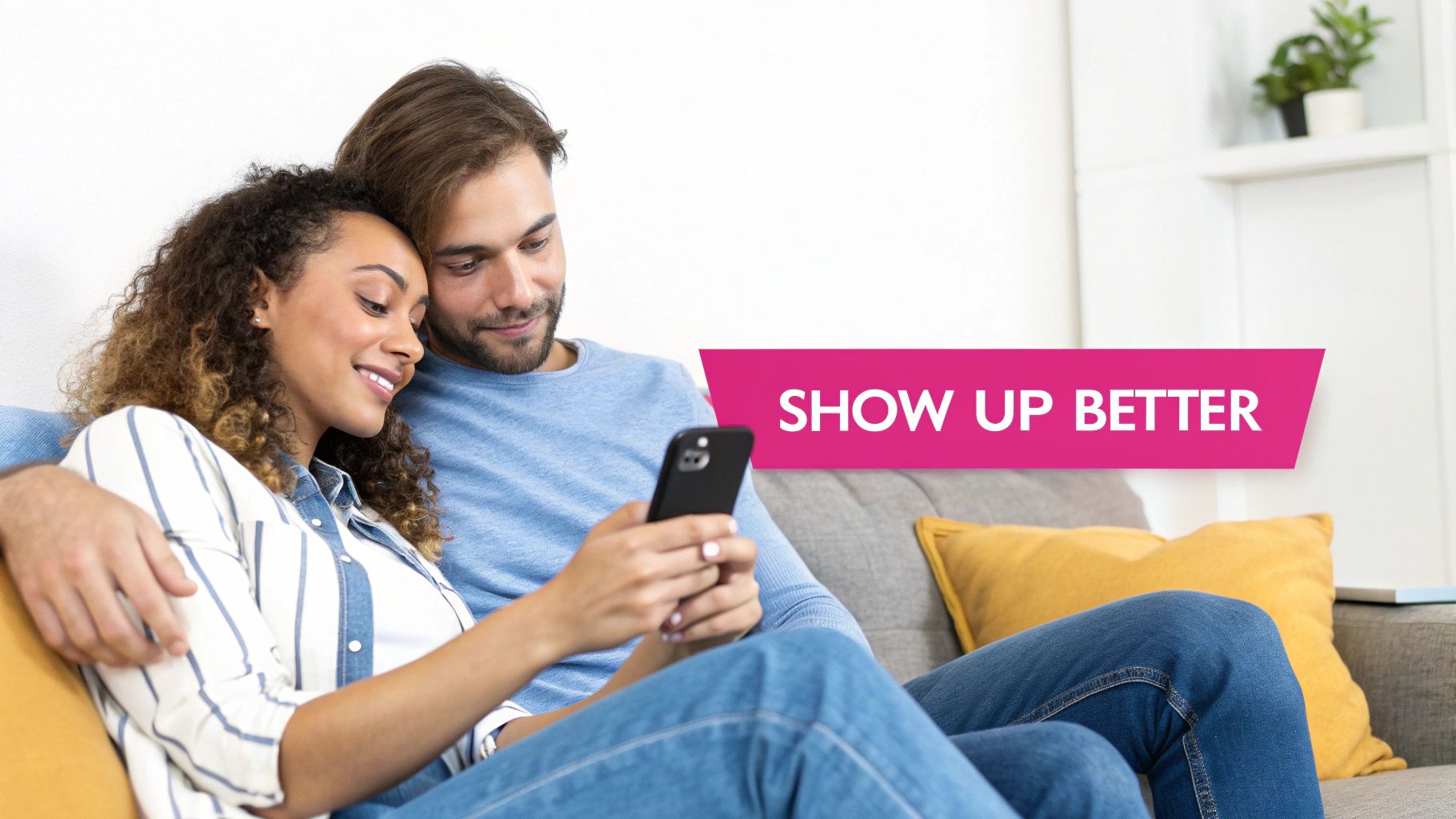 A happy diverse couple sitting together on a couch, looking at a smartphone.
