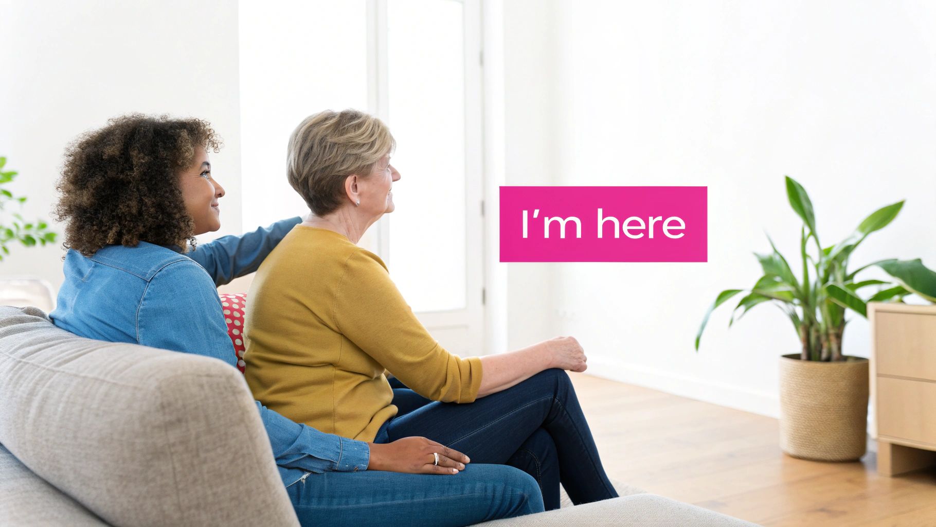 A young woman comforts an older woman on a sofa, looking right, with text 'I'm here'.
