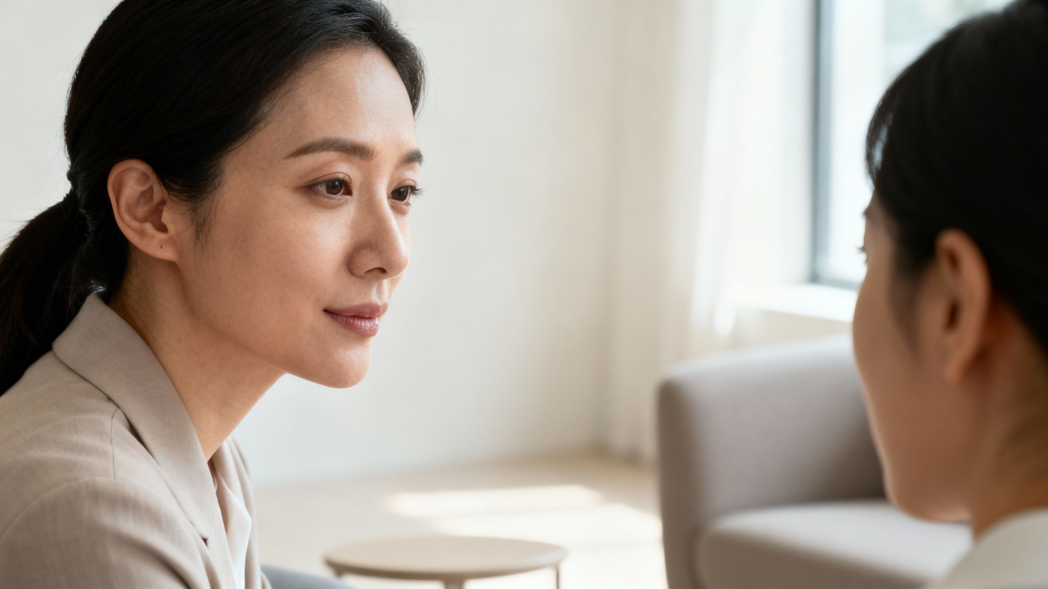 Close-up of a focused woman attentively listening to another person in a therapy session.