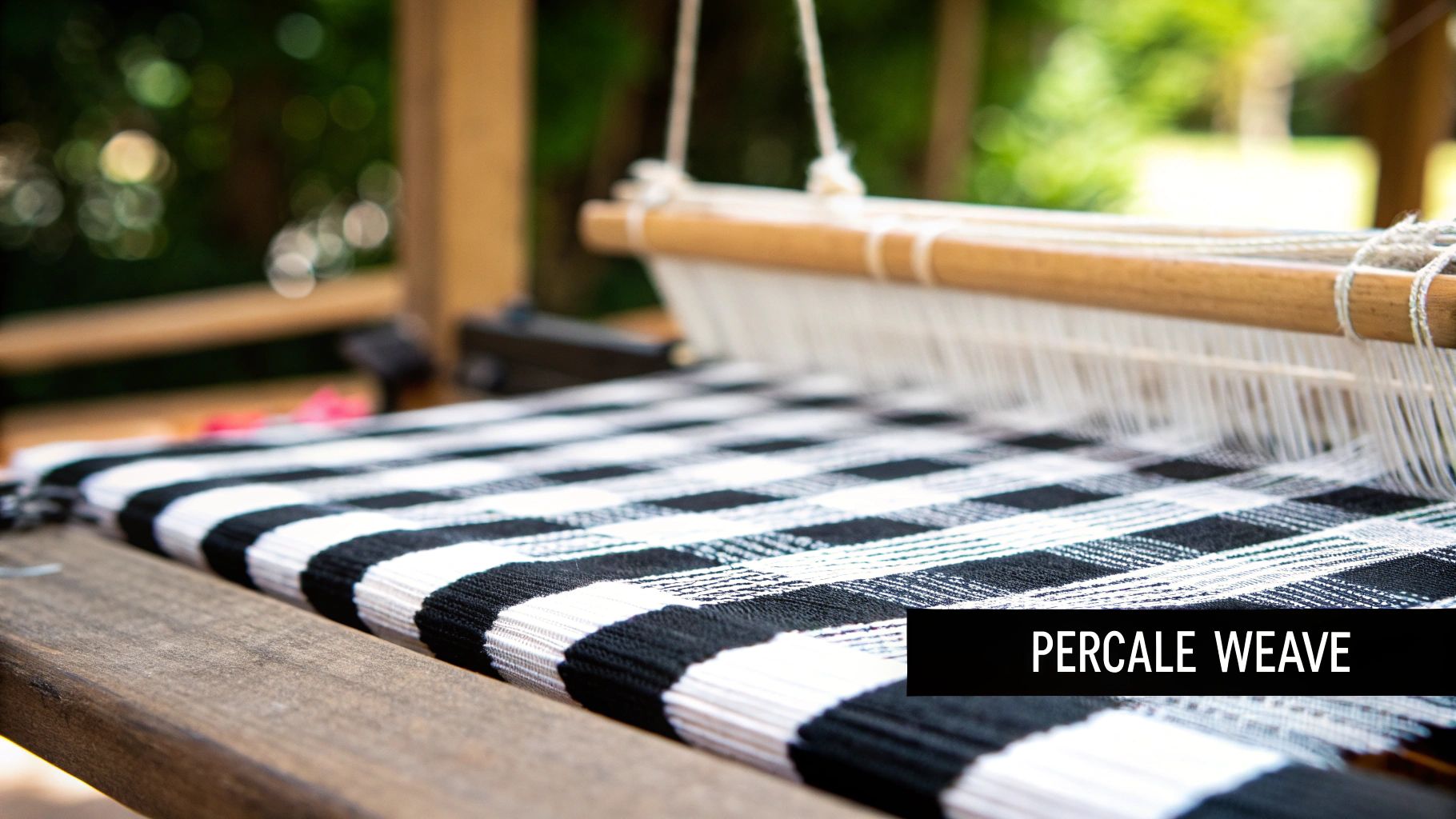 Percale weave fabric on wooden loom showing black and white striped cotton textile pattern