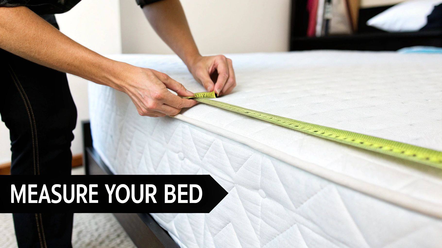 A person measures the width of a white mattress with a yellow fabric tape measure on a bed frame.