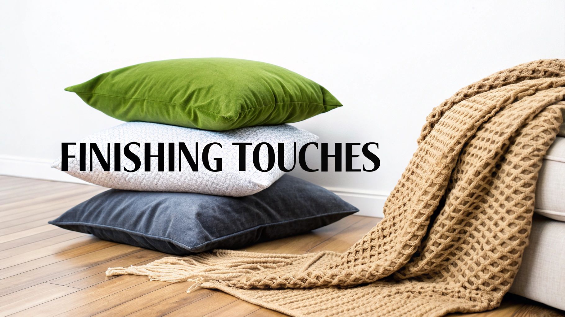 A cozy home scene with stacked decorative pillows and a textured throw blanket on a wooden floor.