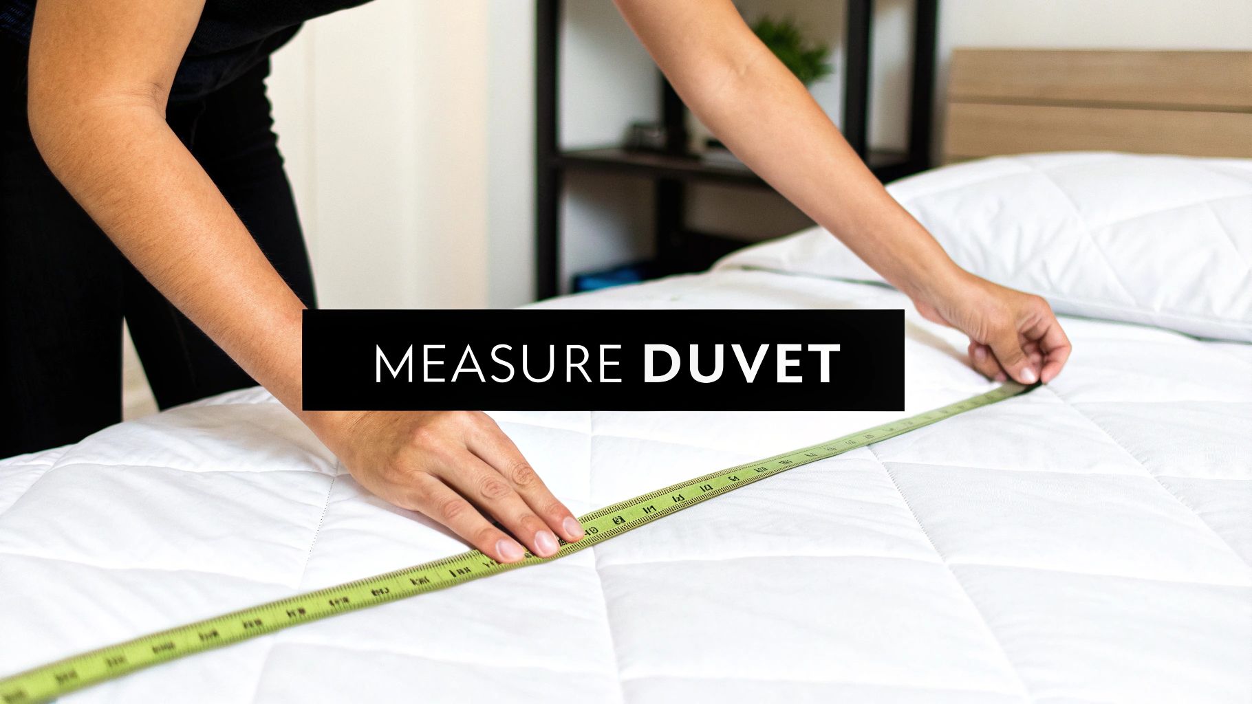 Close-up of hands using a measuring tape to size a white quilted duvet on a bed.