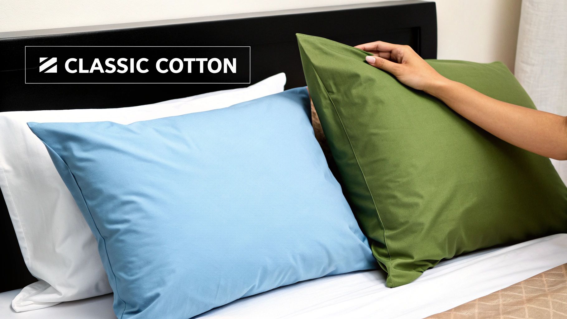 A hand touches a green pillow, with blue and white cotton pillows visible on a bed, featuring a "CLASSIC COTTON" label.
