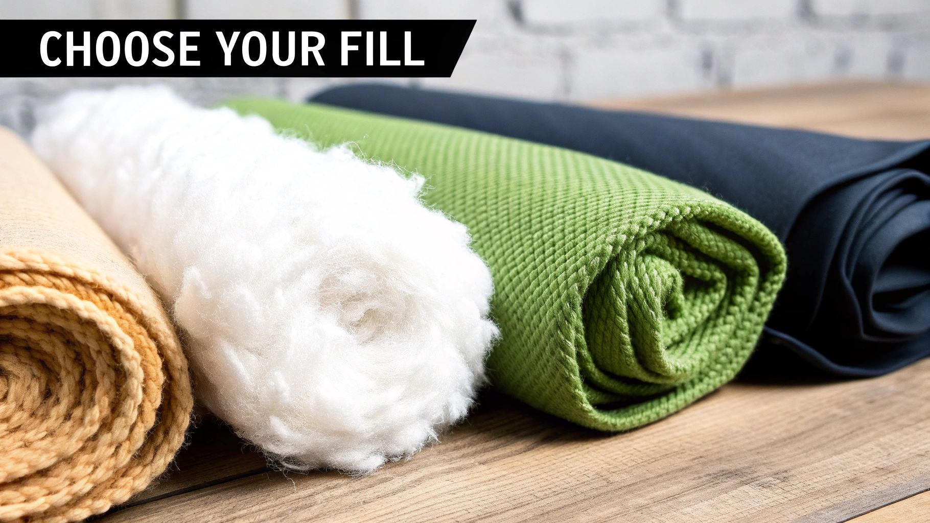 Four rolls of various materials: beige fabric, white fluffy fill, green textured fabric, and dark blue fabric on wood.